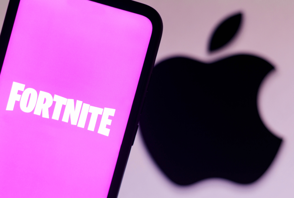 A smartphone screen displaying the logo for Fortnite with the Apple logo in soft focus in the background.