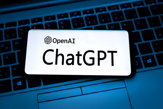 Smartphone with OpenAI's ChatGPT logo displayed on the screen, resting on a laptop keyboard.