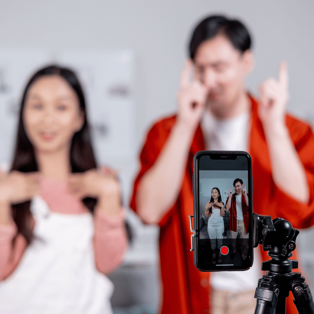 Two people recording a dance for an Instagram Reel, with the smartphone screen showing them in action, mounted on a tripod.