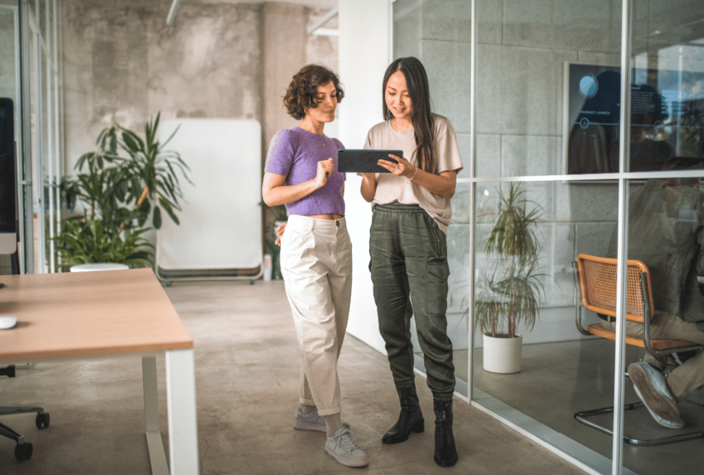 Two professionals discussing over a tablet in a modern office space.