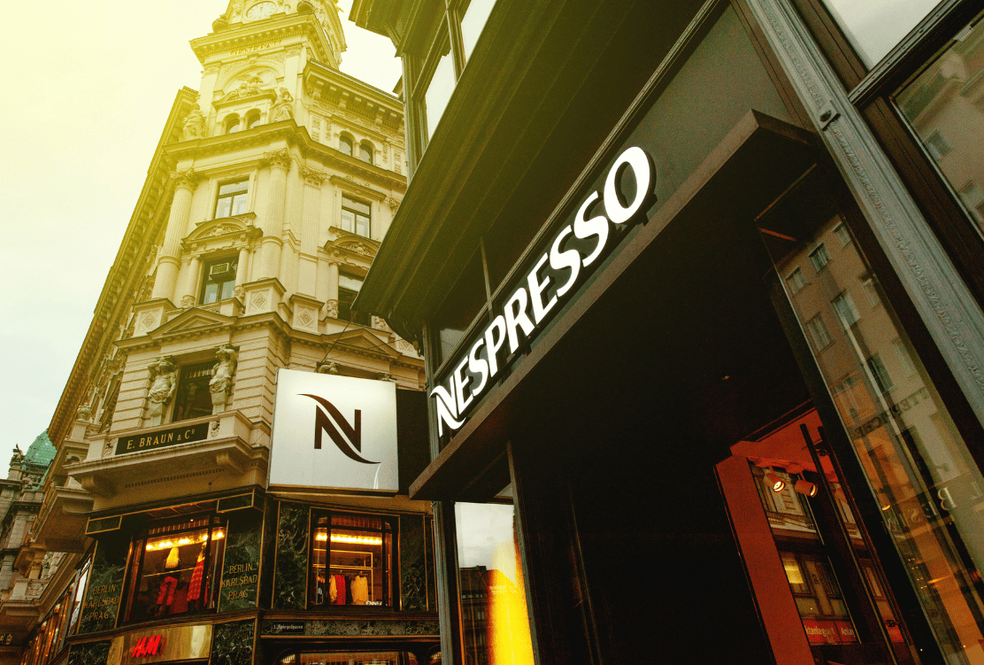 Nespresso storefront sign illuminated on a classic building facade.