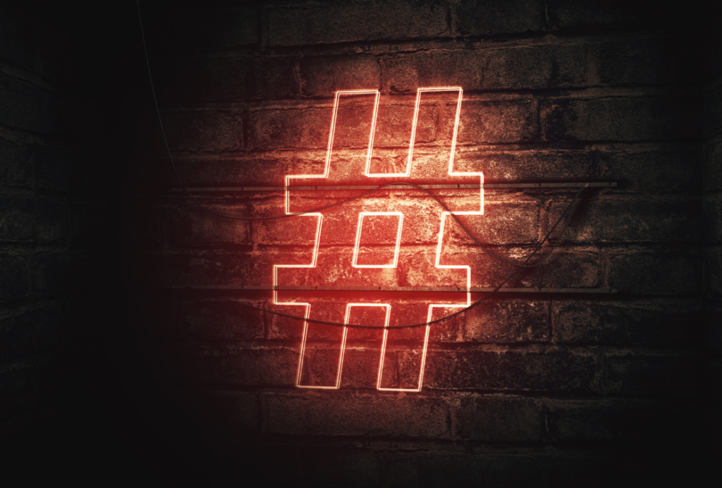 eon hashtag sign glowing against a dark brick wall.